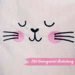 Close-up van het geborduurde konijnengezichtje met roze wangen op de zachte fluwelen stof van het tasje