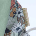 Close-up van de hoogwaardige groene katoenen stof met bloemenmotief en het textiele merklabel van het paasrugzakje