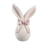 Vooraanzicht van een minimalistisch wit paasbeeldje met grote oren en een glanzende roze strik