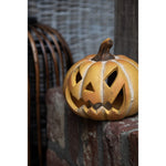 Oranje keramieken Halloween pompoen met uitgesneden gezicht in een donker herfstinterieur
