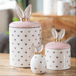 Luxe set van witte voorraadpotten en een decoratie ei met gouden hartjes en konijnenoren in een modern interieur