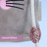 Detailopname van de zachte, harige bruine fluwelen stof en het gedetailleerde borduurwerk van het slapende konijnengezichtje