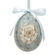 Hangend paasei in vintage stijl met een grote witte roos op een blauwe achtergrond en een blauw strikje