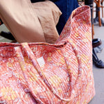 Ruime weekendtas met bloemenmotief staat op de grond bij een terrasje, ideaal als handbagage of strandtas.