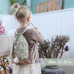 Kind draagt het groene katoenen paasrugzakje met bloemenprint op de rug tijdens het versieren van de paastakken