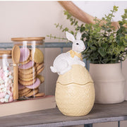 Geel decoratief paasei met wit konijn in een sfeervolle keuken naast een pot met koekjes