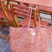 Overzicht van een terras met houten tafels en de Bonheur du Jour weekendtas prominent in beeld.