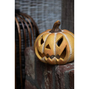 Oranje keramieken Halloween pompoen met uitgesneden gezicht in een donker herfstinterieur