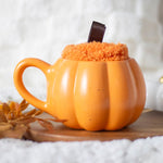 Oranje pompoen mok met fluffy sokken in herfstsetting