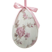 Close up van een wit hangend paasei met een verfijnde roze bloemenprint en een roze satijnen lintje