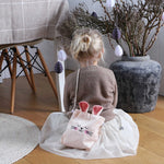 Sfeerbeeld van een kind met een roze velvet schoudertasje met konijnenoren tijdens het versieren van de paastak