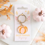 Pompoen sleutelhanger in roze en oranje tussen herfstdecoratie