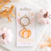 Pompoen sleutelhanger in roze en oranje tussen herfstdecoratie