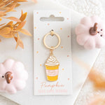 Pumpkin Spice Latte sleutelhanger tussen roze pompoenen als herfstcadeautje