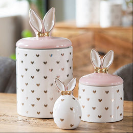 Luxe set van witte voorraadpotten en een decoratie ei met gouden hartjes en konijnenoren in een modern interieur