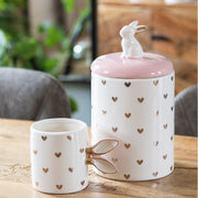 Keramische voorraadpot met roze deksel en bijpassende mok in een modern voorjaar interieur