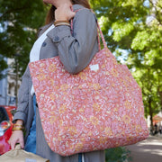 Vrouw in geruite jas draagt de grote Bonheur du Jour shopper, perfecte tas voor een citytrip of dagelijks gebruik.