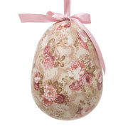 Close up van een groot beige paasei met een gedetailleerde roze rozenprint en een roze satijnen lintje