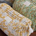 Close-up van de doorgestikte (quilted) katoenen stof met bloemenprint van de gele en groene beautycases.