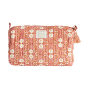 Vrijstaande productfoto van een okergele en oranje quilted toilettas met een verfijnde bloemenprint en een  decoratief kwastje.